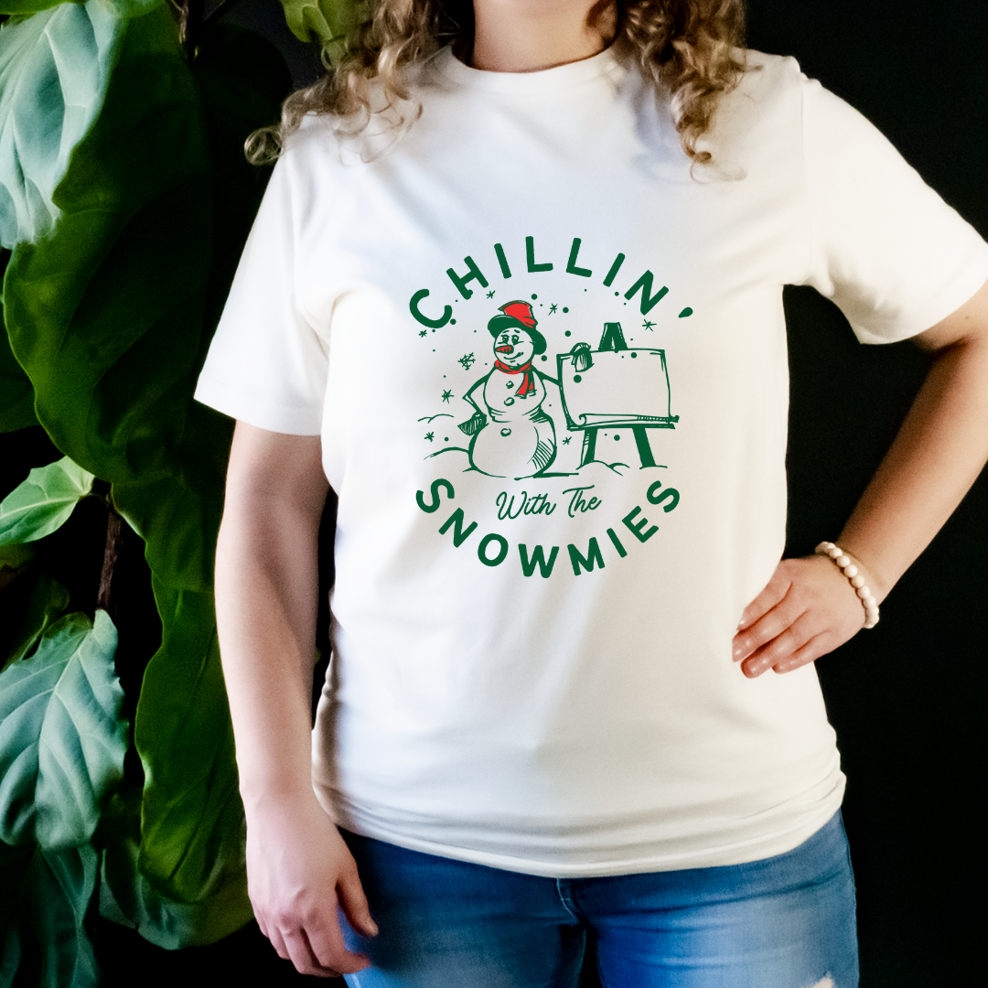 "Chillin' with the snowmies text design centered on natural t-shirt."