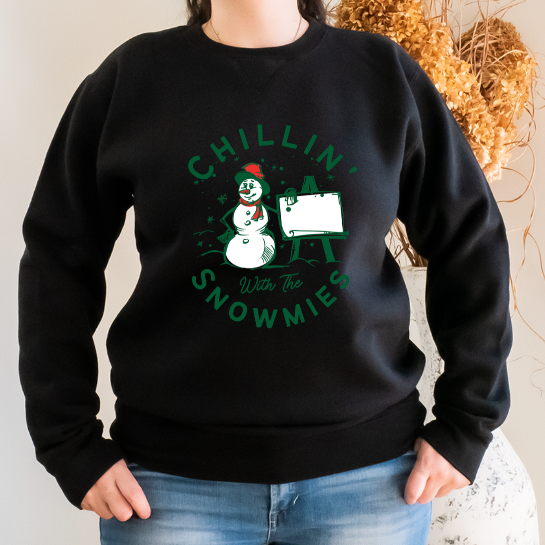 "Chillin' with the snowmies text design centered on black sweater."