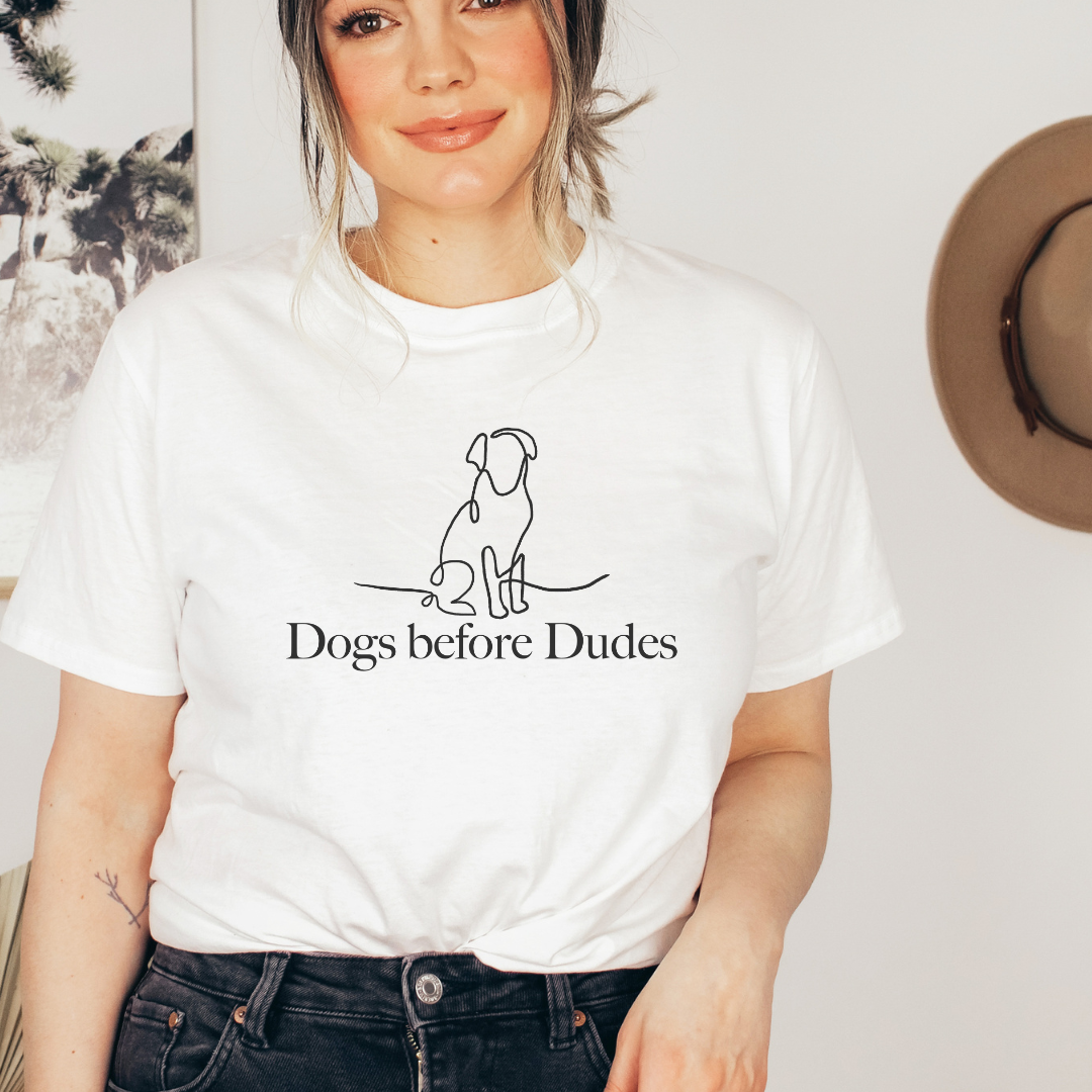 "Dogs before dudes text and graphic design centered on white t-shirt."