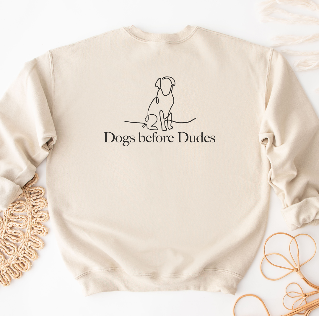 "Dogs before dudes text and graphic design centered on natural sweater."