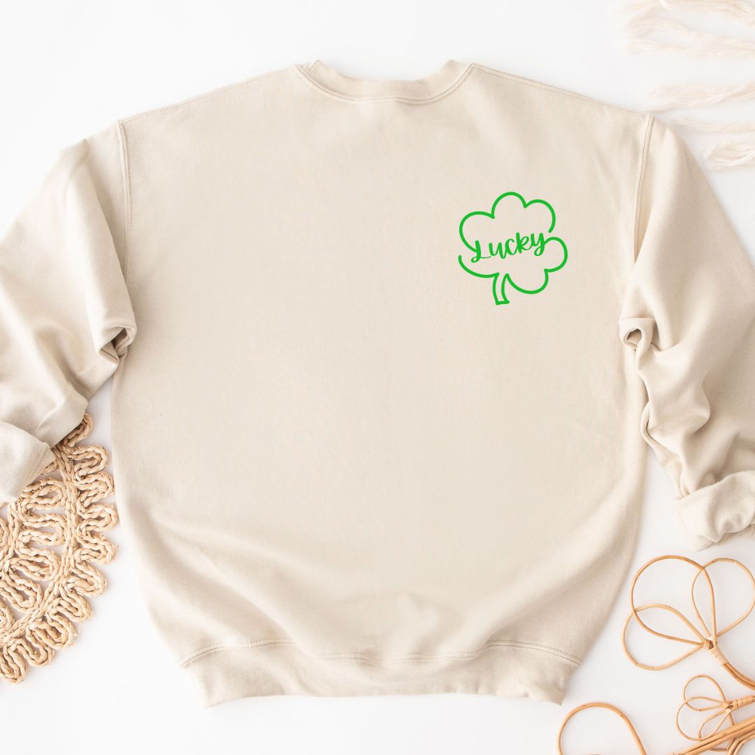 "Lucky Clover graphic design centered on natural sweater."